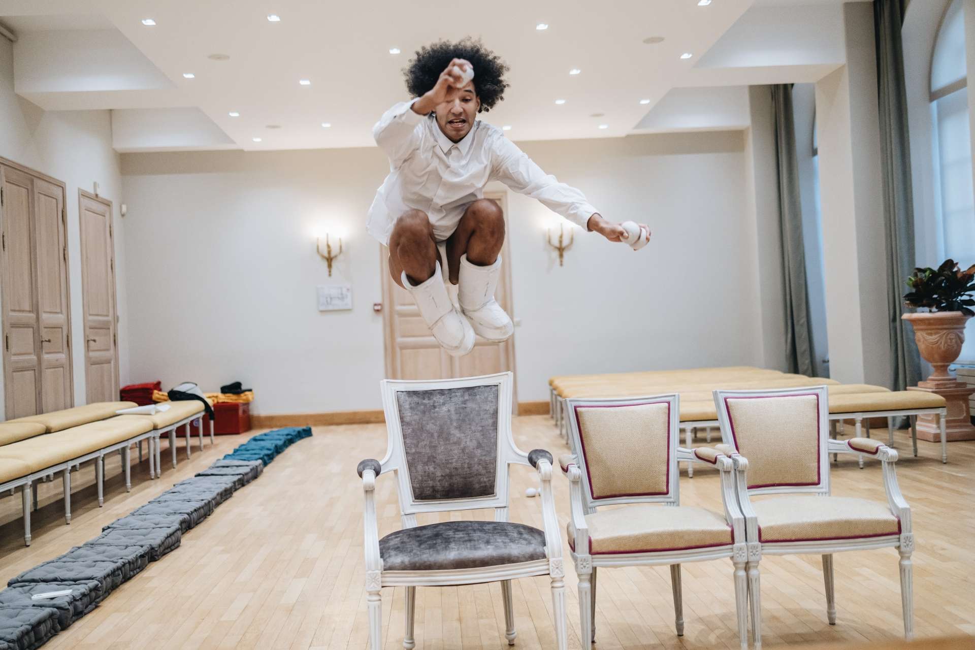L'artiste Guillaume Martinet saute par-dessus un fauteuil dans la salle des mariages de l'hôtel de ville