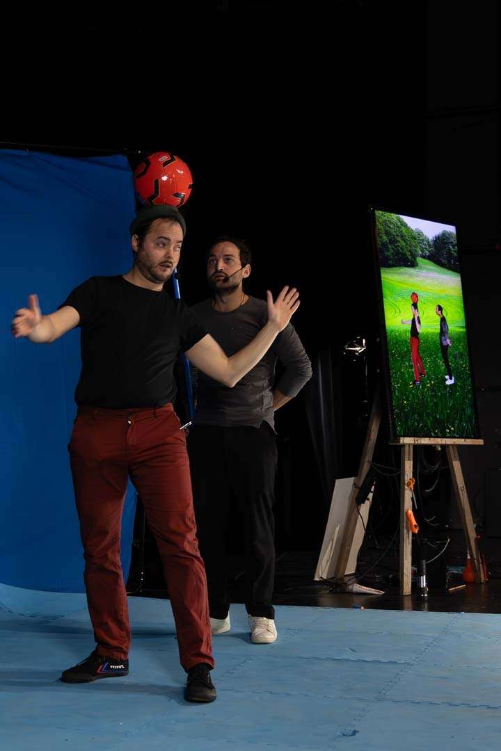 Un acrobate tient un ballon sur sa tête devant un écran bleu
