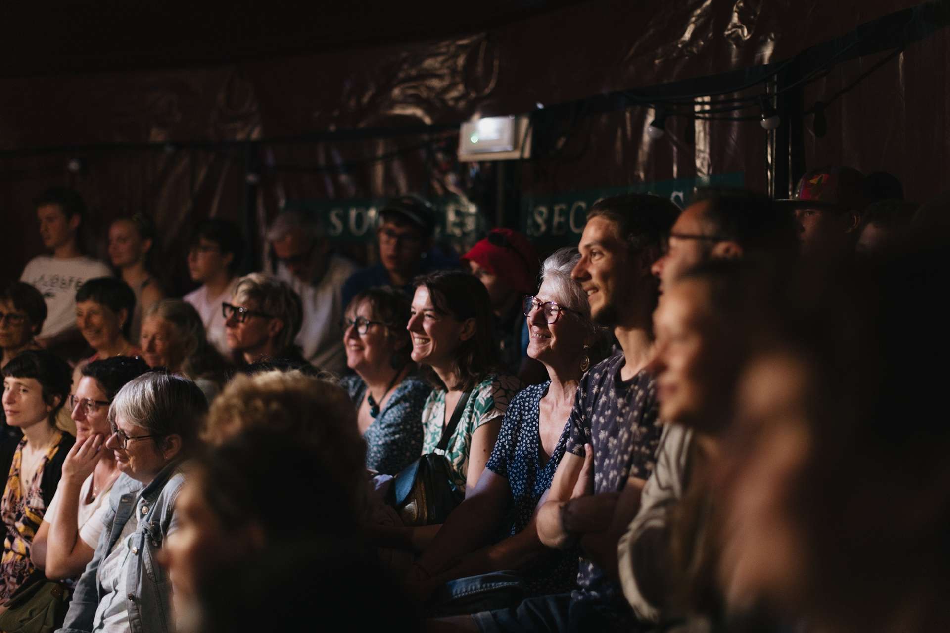 Des spectateurs rient sous un chapiteau