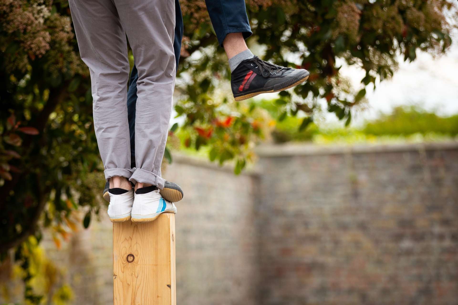 Les pieds de deux hommes juchés sur un bastaing de bois