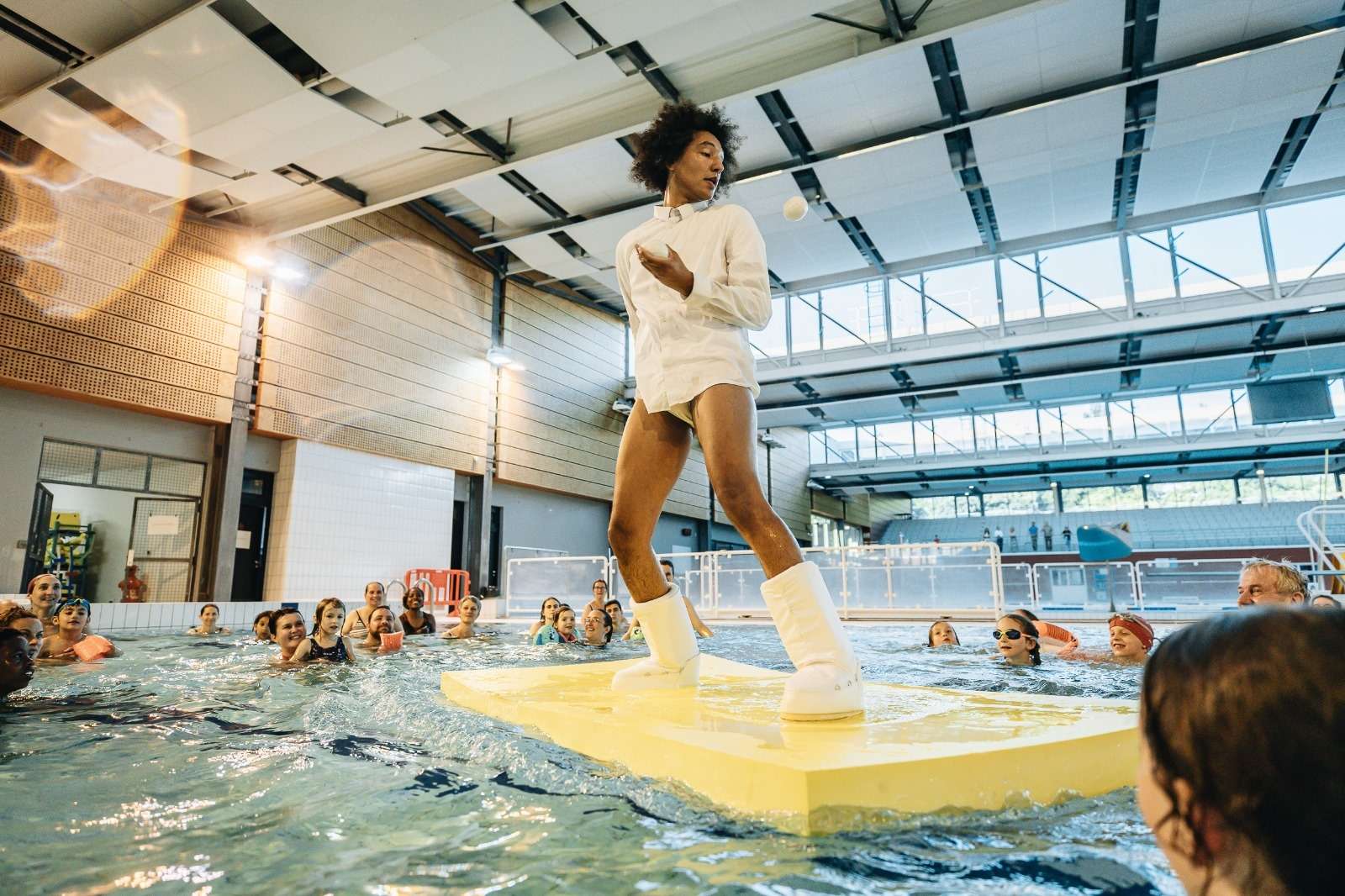 Un artiste traverse le bassin de la piscine debout sur un tapis