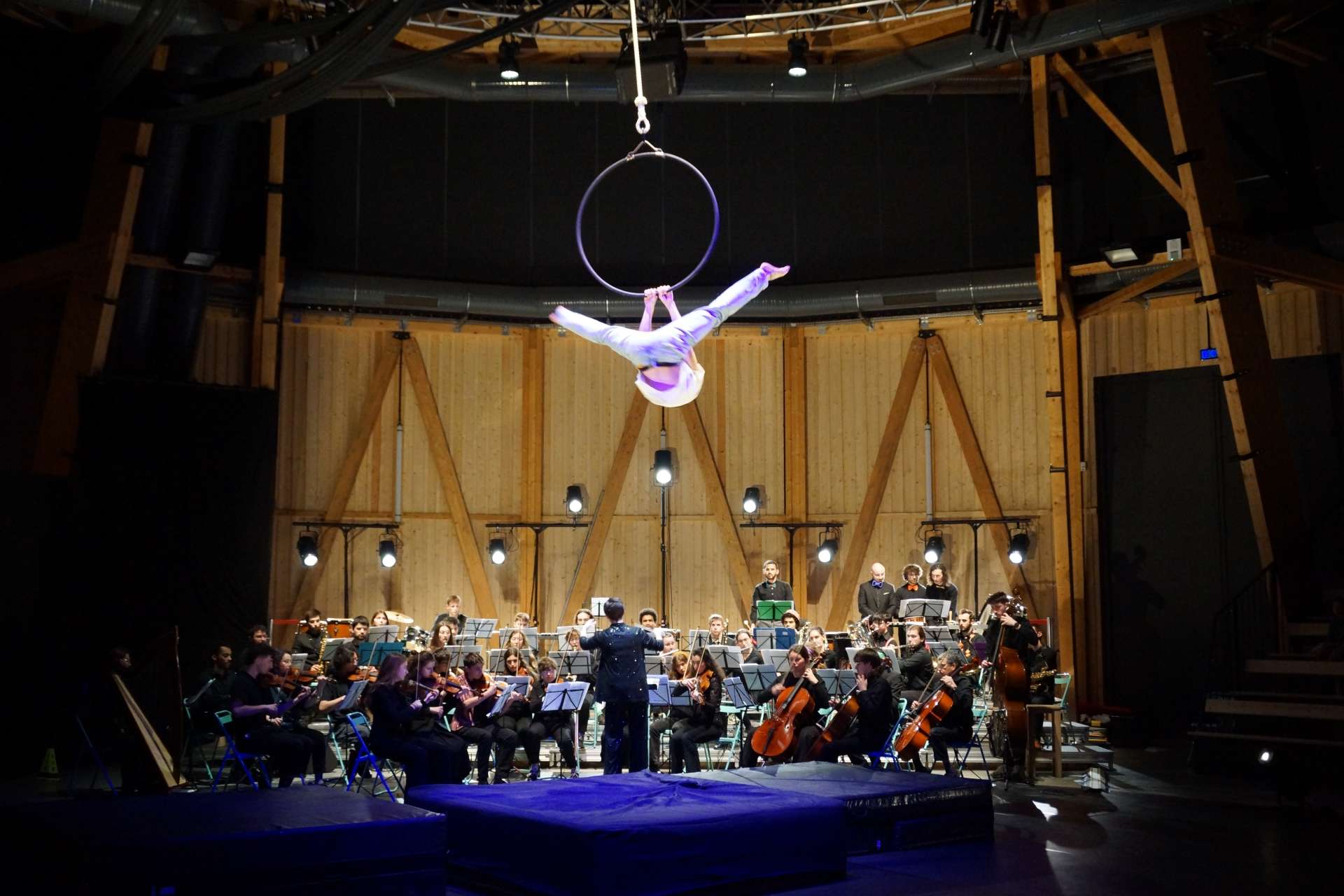 acrobate suspendue à un cerceau avec orchestre sous elle