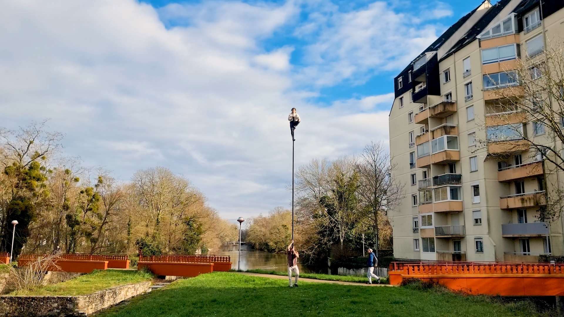 une personne tiens une autre au sommet d'un mat