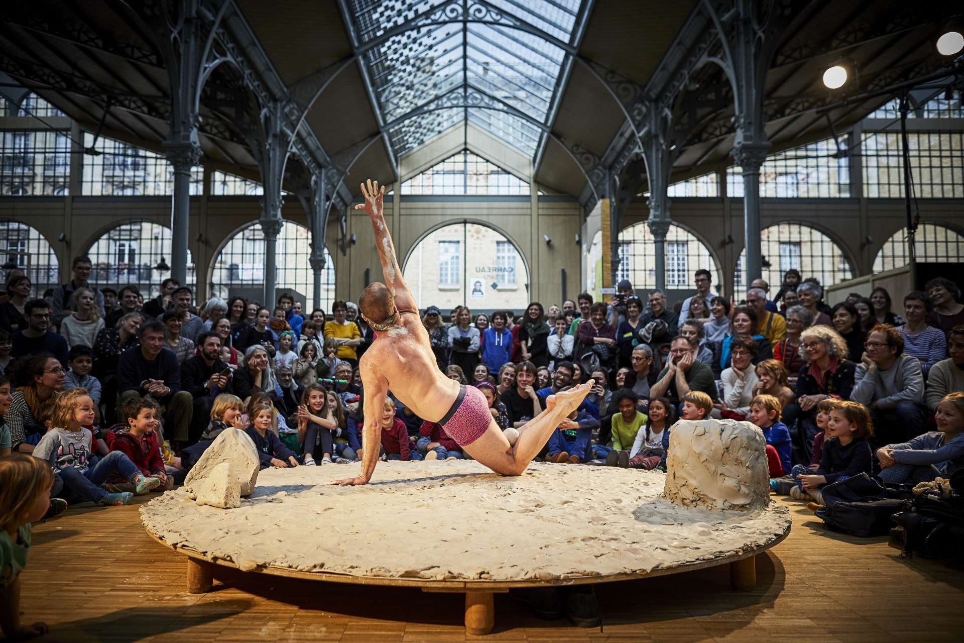 un homme posse au milieu d'un plateau circulaire recouvert de gadoue