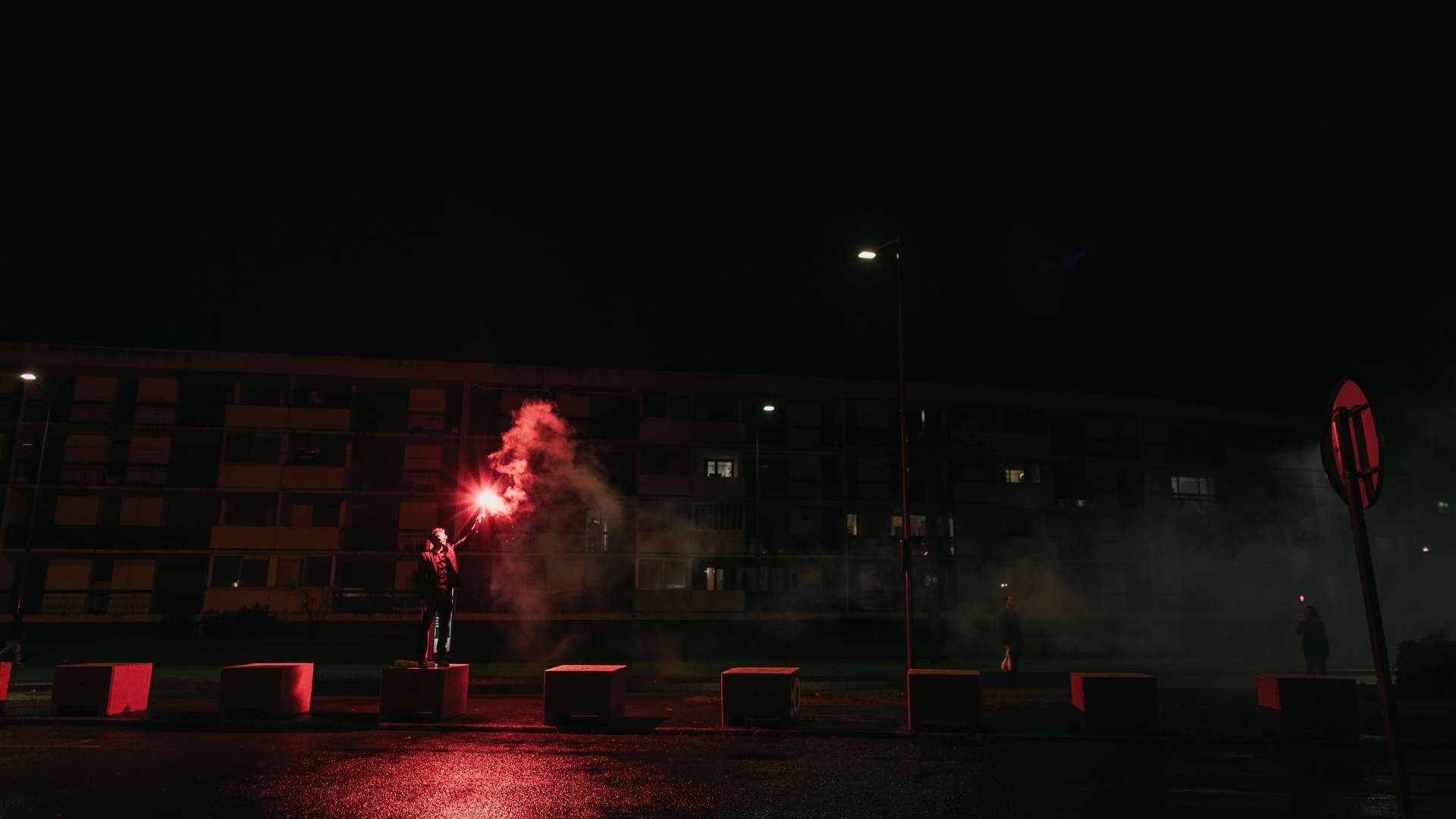 Un homme tient un fumigène dans la nuit